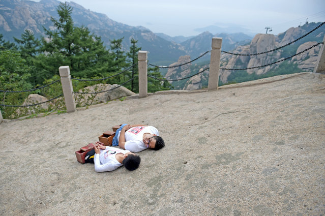 Gao Zhiyu (L) and Chen Zhou, who lost both of their legs during accidents, take a rest as they climb mountain Lao in Qingdao, Shandong Province, China, September 10, 2016. (Photo by Reuters/Stringer)