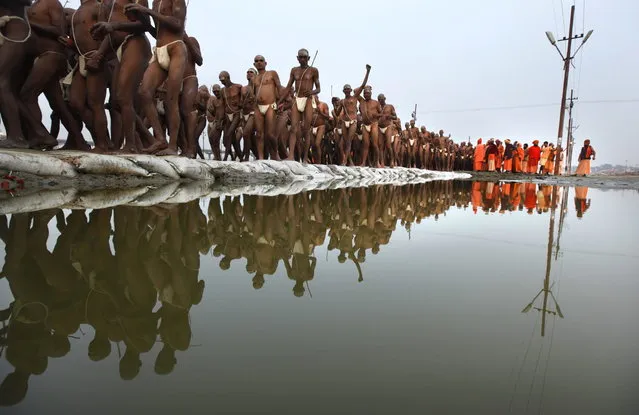 Hindu holy men of the Juna Akhara sect return after rituals that are believed to rid them of all ties in this life and dedicate themselves to serving God as a “Naga” or naked holy men, at Sangam, the confluence of the Ganges and Yamuna River during the Maha Kumbh festival in Allahabad, India, Wednesday, February 6, 2013. The significance of nakedness is that they will not have any worldly ties to material belongings, even something as simple as clothes. This ritual that transforms selected holy men to Naga can only be done at the Kumbh festival.(Photo by Rajesh Kumar Singh/AP Photo)