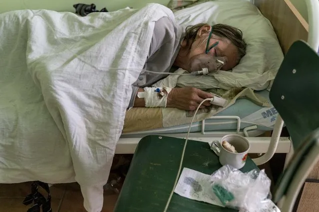 A patient with coronavirus breathes with an oxygen mask in a hospital intensive care unit in Stryi, Ukraine, on Tuesday, September 29, 2020. Coronavirus infections in Ukraine began surging in late summer, and the ripples are hitting towns in the western part of the country. The government wants to avoid imposing a new lockdown, but officials acknowledge that the rising infections could make it necessary. (Photo by Evgeniy Maloletka/AP Photo)