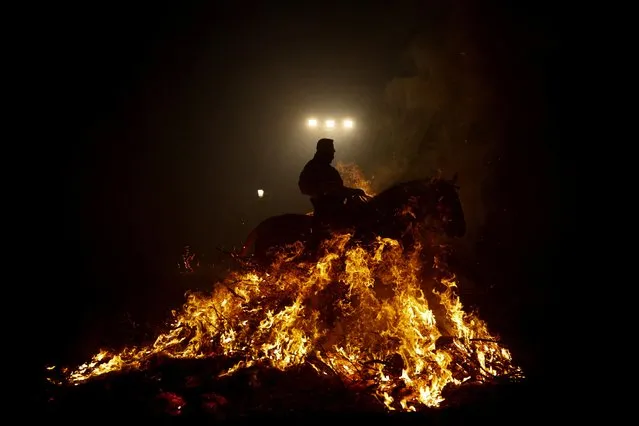 A rider goes through flames during the annual “Luminarias” celebration on the eve of Saint Anthony's day, Spain's patron saint of animals, in the village of San Bartolome de Pinares, northwest of Madrid, Spain on January 16, 2023. (Photo by Susana Vera/Reuters)