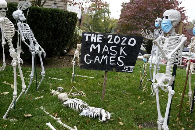 In this October 22, 2020, file photo, coronavirus-themed Halloween decorations are displayed on a lawn in Tenafly, N.J. In a year when fear and death have commandeered front-row seats in American life, what does it mean to encounter Halloween, a holiday whose very existence hinges on turning fear and death into entertainment? (Photo by Seth Wenig/AP Photo/File)