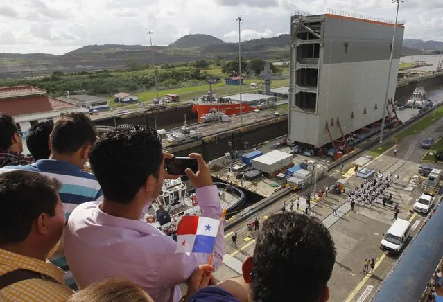 People take pictures as tugboats help a barge transporting the last rolling gate for the new locks on the Pacific side of the Panama Canal through the Miraflores locks in Panama City December 10, 2014. According to Panama Canal authorities, the Panama Canal's fourth set of locks has 16 rolling gates, eight for each new lock complex. (Photo by Rafael Ibarra/Reuters)