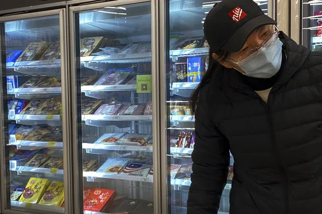 A woman wearing a face mask to help curb the spread of the coronavirus walks by a fridge displaying frozen meats at a supermarket in Beijing, Tuesday, November 24, 2020. China has stirred controversy with claims it has detected the coronavirus on packages of imported frozen food. (Photo by Andy Wong/AP Photo)