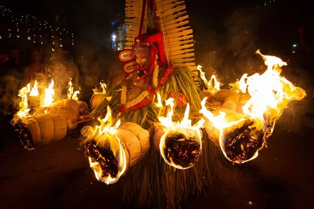 A man dressed in the likeness of the Hindu deity Agni Kandakarnan performs during the Theyyam ritualistic dance festival on March 14, 2023 in Somwarpet, India. Theyyam is a colourful socioreligious dance form that is the amalgamation of ritual, vocal and instrumental music, dance, painting, and literature and its genesis can be traced to the coastal regions of the southern Indian states of Kerala and Karnataka. (Photo by Abhishek Chinnappa/Getty Images)