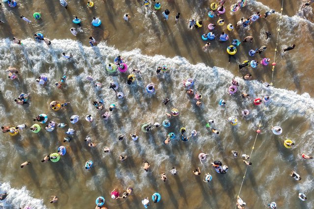 An aerial view shows people cooling off on a beach in Qingdao, in eastern China's Shandong province on August 18, 2025. (Photo by AFP Photo/China Stringer Network)