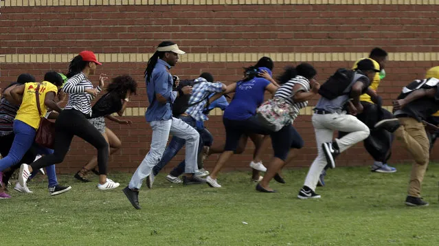 Protesting students run for cover as riot police officers fire rubber bullets at the Vaal University of Technology in Vanderbijlpark, South Africa, on Friday, October 14, 2016. The campus has been the scene of clashes between police and students demonstrating for free university education. (Photo by Themba Hadebe/AP Photo)