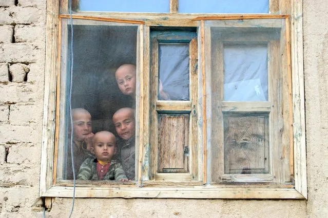 Afghan boys look from a window of their house in Yaftal Sufla district of Badakhshan province on March 12, 2023. (Photo by Omer Abrar/AFP Photo)