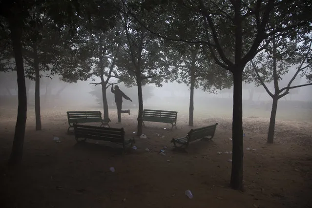 An Indian man exercises as fog envelops a park in New Delhi, India, Monday, December 22, 2014. Cold wave conditions intensified across northern India as temperatures dipped along with thick blankets of fog cutting out sunlight for long hours. (Photo by Tsering Topgyal/AP Photo)