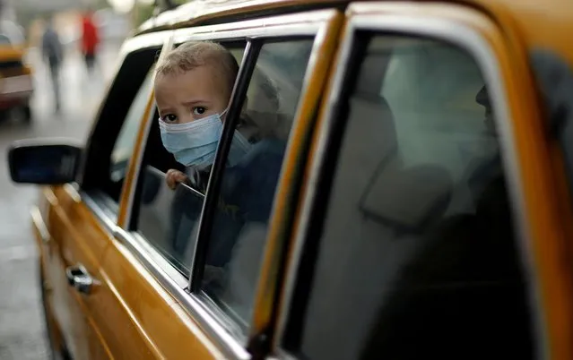 A boy wearing a protective face mask looks out of a car as he waits to leave the Palestinian Rafah border crossing with Egypt, which was reopened partially amid the spread of the coronavirus disease (COVID-19), in the southern Gaza Strip on November 2, 2020. (Photo by Suhaib Salem/Reuters)