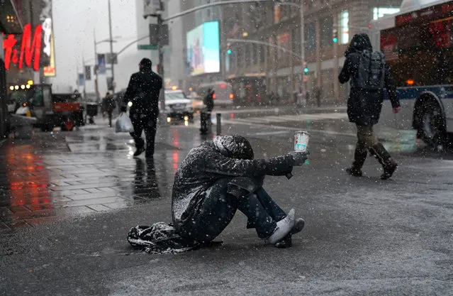A man begs for money in the snow along 42nd Street in Times Square in New York on March 21, 2018, as  the fourth nor'easter in a month hits the tri-state area on the first full day of spring. (Photo by Timothy A. Clary/AFP Photo)