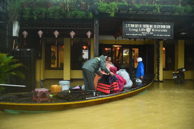 People are evacuated from a hotel on a boat in flood waters following heavy rains in Hoi An in central Vietnam on October 27, 2025. (Photo by Hai Van/AFP Photo)