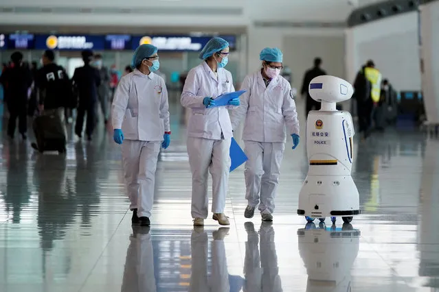 Medical workers walk by a police robot at the Wuhan Tianhe International Airport after travel restrictions to leave Wuhan, the capital of Hubei province and China's epicentre of the novel coronavirus disease (COVID-19) outbreak, were lifted, April 8, 2020. (Photo by Aly Song/Reuters)