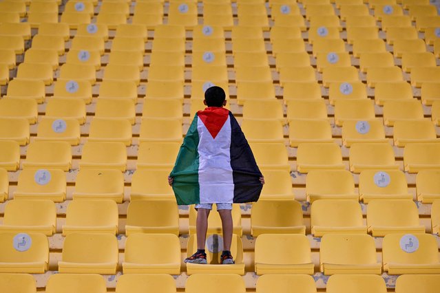 A fan shows a Palestinian flag during the FIFA Arab Cup 2025 play-off football match between Libya and Palestine at Al Gharafa Stadium in Al-Rayyan on November 25, 2025. (Photo by Mahmud Hams/AFP Photo)