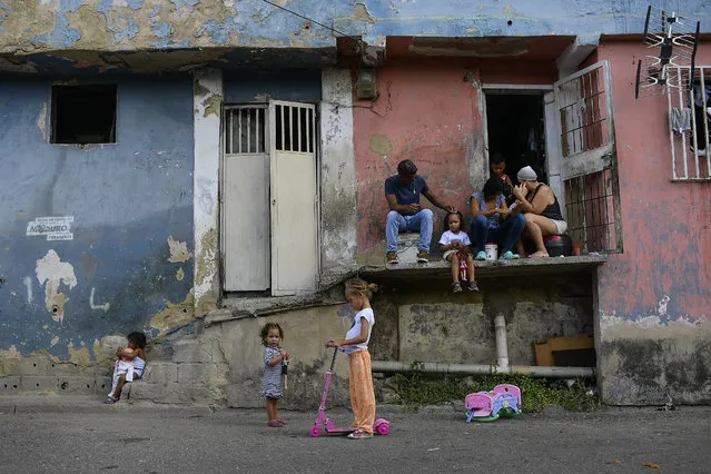 Girls play with their toys as their parents rest outside of their home in Petare neighborhood on Christmas Day in Caracas, Venezuela, Friday, December 25, 2020, amid the new coronavirus pandemic. (Photo by Matias Delacroix/AP Photo)