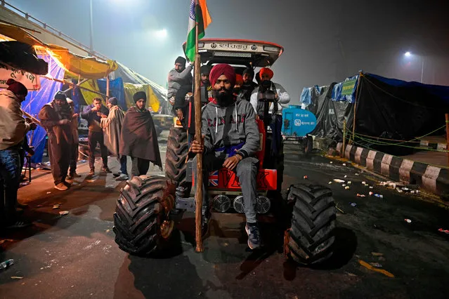 Farmers sit on a tractor along a blocked highway as they continue to protest against the central government's recent agricultural reforms at the Delhi-Uttar Pradesh state border in Ghazipur on January 29, 2021. (Photo by Sajjad Hussain/AFP Photo)