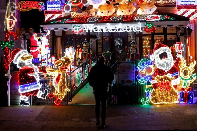 A man looks at a residential house illuminated with Christmas lights in Dublin, Ireland on December 9, 2024. (Photo by Clodagh Kilcoyne/Reuters)