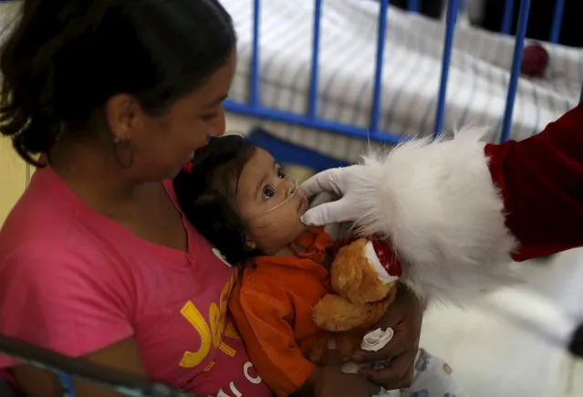 A man dressed as Santa Claus touches a baby at the San Juan de Dios Hospital in Guatemala City, December 16, 2015. The hospital organises the event annually where Santa Claus distributes gifts to children receiving medical attention. (Photo by Jorge Dan Lopez/Reuters)