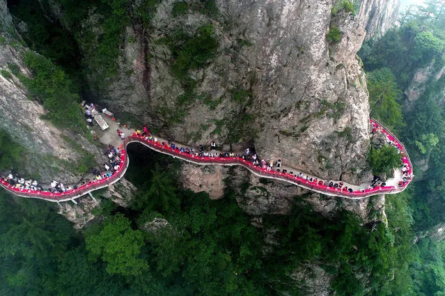 This photo taken on July 8, 2018 shows an aerial view of a banquet held along the edge of a cliff, at Laojun Mountain in Luoyang in China's central Henan province.
The banquet was held on a mountain cliff 2,000-metres (6,500-ft.) above sea level to attract tourists. (Photo by AFP Photo/Stringer)