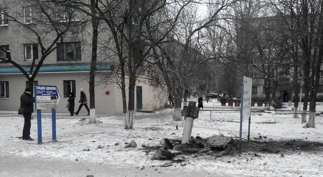 A resident passes by an unexploded rocket in a living area in Kramatorsk, Ukraine, Tuesday, February10, 2015.  (Photo by AP Photo)