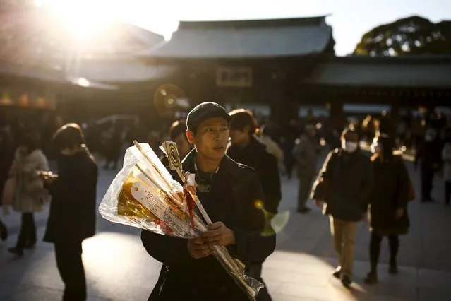 A man holds Hamaya arrows, sold on New Year at the shrine as good-luck charms at the Shinto Meiji Shrine in Tokyo, Japan, January 1, 2016. (Photo by Thomas Peter/Reuters)