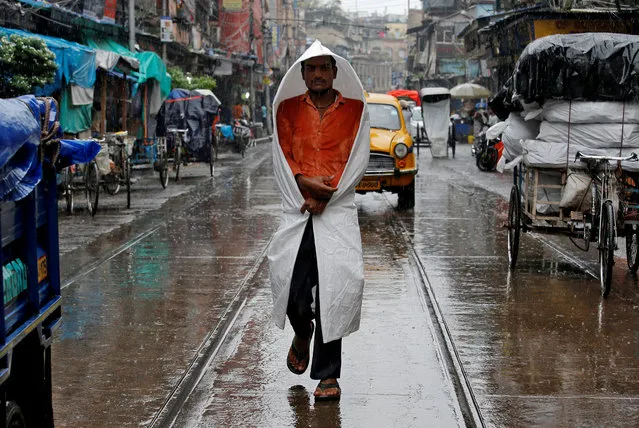 A man covers himself with a plastic sheet as he walks through a street during rain in Kolkata, India on August 31, 2018. (Photo by Rupak De Chowdhuri/Reuters)
