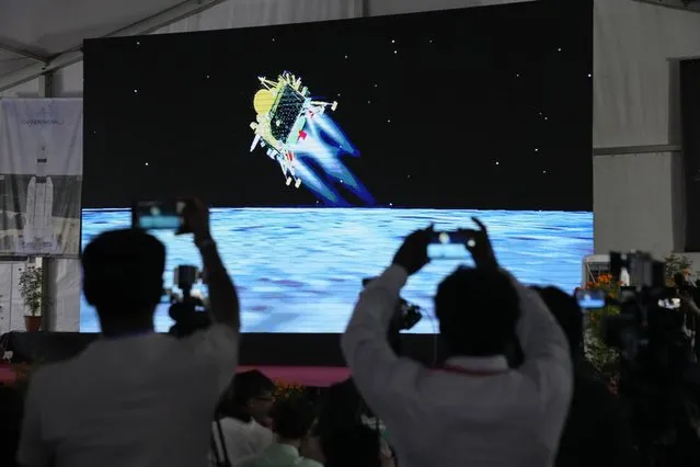 Journalists film the live telecast of spacecraft Chandrayaan-3 landing on the moon at ISRO's Telemetry, Tracking and Command Network facility in Bengaluru, India, Wednesday, August 23, 2023. India lands a spacecraft near the moon's south pole, becoming the fourth country to touch down on the lunar surface. (Photo by Aijaz Rahi/AP Photo)
