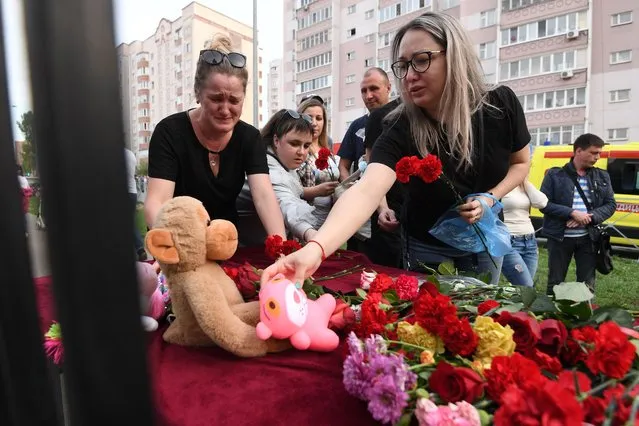 A woman places a toy at a makeshift memorial for victims of the shooting at School No. 175 in Kazan on May 11, 2021. At least nine people, most of them children, were killed on May 11, 2021 when a lone teenage gunman opened fire at a school in the central Russian city of Kazan, officials said. (Photo by Natalia Kolesnikova/AFP Photo)