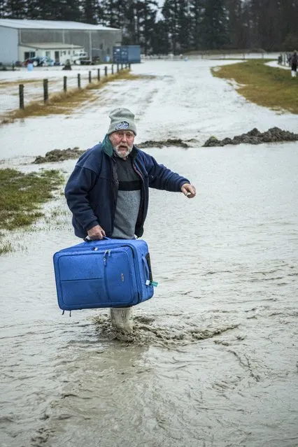 A man carries his suitcase as he is evacuated from floods by New Zealand Defense Force personnel near Ashburton in New Zealand's South Island, Sunday May 30, 2021. (Photo by Corp. Sean Spivey/NZDF via AP Photo)