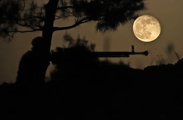 April's Pink Super Moon rises behind a fighter of the Turkish-backed Free Syrian Army in the rebel-held southern countryside of Syria's northwestern province of Idlib on April 28, 2021. (Photo by Abdulaziz Ketaz/AFP Photo)