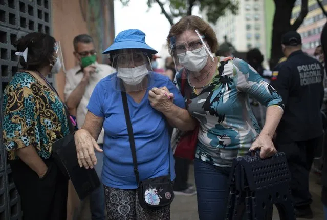 Two elderly women walk into the Alba Caracas hotel to get their first dose of the Sputnik V COVID-19 vaccine after being in line for more than 5 hours, during a massive vaccination campaign for seniors in Caracas, Venezuela, Monday, May 31, 2021. (Photo by Ariana Cubillos/AP Photo)