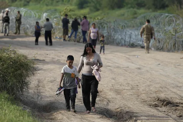 Migrants who crossed into the U.S. from Mexico walk past concertina wire lining the banks of the Rio Grande as they move to an area for processing, Thursday, September 21, 2023, in Eagle Pass, Texas. (Photo by Eric Gay/AP Photo)