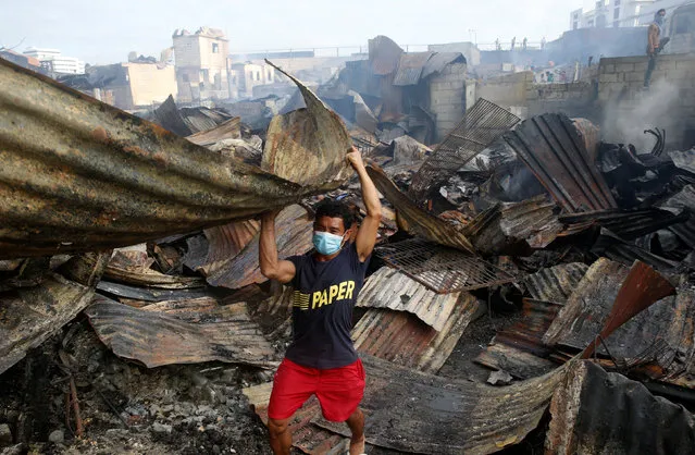 A fire victim collects recyclable materials from the ruins of his house after a fire razed a squatter colony, in Quezon city, Metro Manila in the Philippines December 28, 2016. (Photo by Erik De Castro/Reuters)