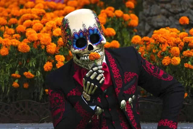 A Mexican mascot dressed as a catrin, a masculine version of the Day of the Dead Catrina, poses for photographers at the Hermanos Rodriguez race track in Mexico City, Thursday, October 26, 2023. The track is hosting the Mexico City Grand Prix which begins Friday.  (Photo by Fernando Llano/AP Photo)