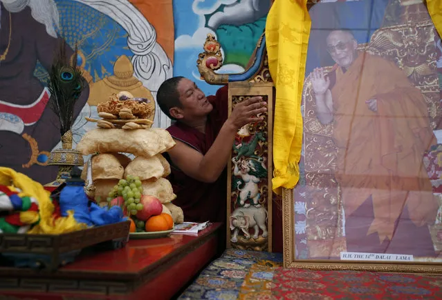 A Tibetan monk arranges the portrait of exiled Tibetan spiritual leader, the Dalai Lama, during a function organised to mark “Losar” or the Tibetan New Year in Kathmandu, Nepal, February 11, 2016. (Photo by Navesh Chitrakar/Reuters)