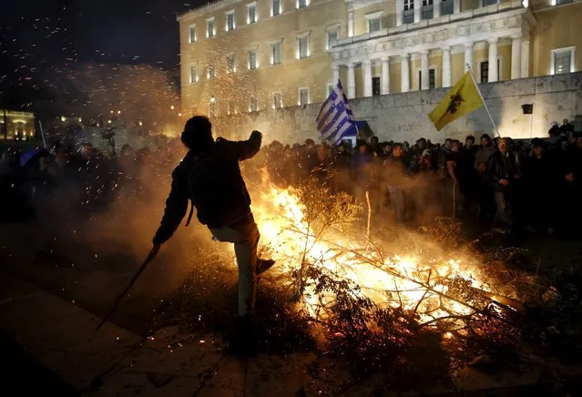 A protester is seen by a fire set by angry farmers outside the parliament during a protest against planned pension reforms in Athens, Greece February 12, 2016. (Photo by Yannis Behrakis/Reuters)