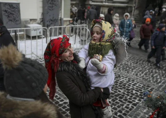 A child dressed in a traditional costume eats a pampukh, a Ukrainian Christmas doughnut, as she celebrates Orthodox Christmas with her mother in Lviv, Ukraine January 6, 2017. (Photo by Gleb Garanich/Reuters)