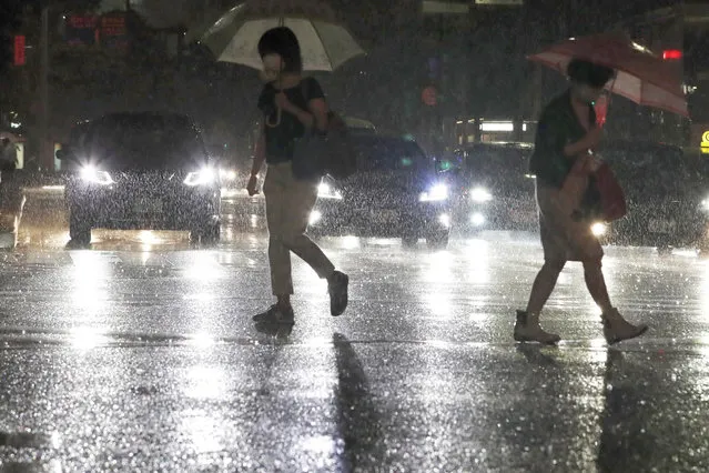 People holding umbrella make their way through heavy rain in Fukuoka, western Japan, Thursday, August 12, 2021. Torrential rain pounding southwestern Japan has triggered a mudslide and swallowed four people in Nagasaki and threatened the region with the risk of floods and more landslides, officials said Friday. (Photo by Kyodo News via AP Photo)
