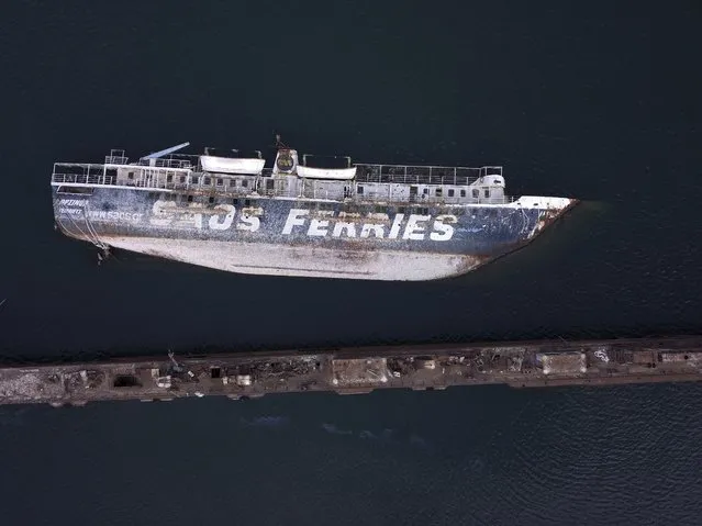 In this Friday, December 4, 2018 photo, a half sunken ferry lays on its side in the Gulf of Elefsina, west of Athens. Dozens of abandoned cargo and passenger ships lie semi-submerged or completely sunken around the Gulf of Elefsina, near Greece’s major port of Piraeus. Now authorities are beginning to remove the dilapidated ships. Some of them have been there for decades, leaking hazards like oil into the environment and creating a danger to modern shipping. One expert calls the abandoned ships “an environmental bomb”. (Photo by Thanassis Stavrakis/AP Photo)