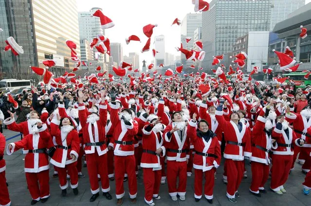 More than 1,000 volunteers clad in Santa Claus costumes throw their hats in the air as they gather to deliver gifts for the poor in downtown Seoul, South Korea, Tuesday, December 24, 2013. (Photo by Lee Jin-man/AP Photo)