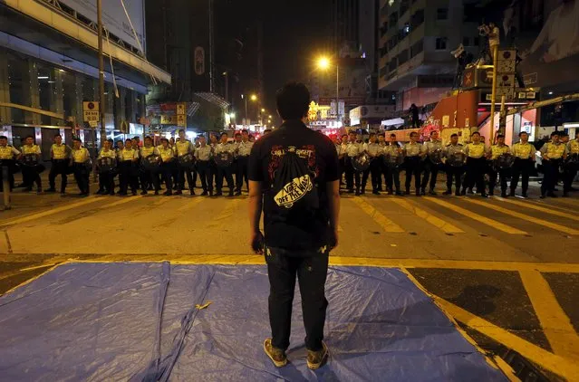 A pro-democracy protester stands in front of a line of riot police at Mongkok shopping district in Hong Kong early, in this October 17, 2014 file photo. (Photo by Bobby Yip/Reuters)