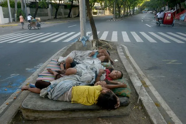 Street children sleep on a discarded mattress on a center island near a road crossing in Manila on April 12, 2015. The world marks International Day for Street Children on April 12 to campaign for the rights of impoverished children. (Photo by Jay Directo/AFP Photo)