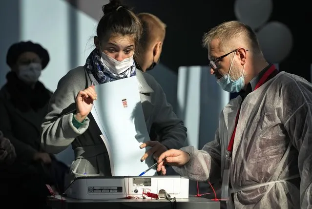 A member of an election commission helps to a woman to casts her ballot during the State Duma, the Lower House of the Russian Parliament and local parliament elections at a polling station in St. Petersburg, Russia, Sunday, September 19, 2021. The head of Russia's Communist Party, the country's second-largest political party, is alleging widespread violations in the election for a new national parliament in which his party is widely expected to gain seats. (Photo by Dmitri Lovetsky/AP Photo)