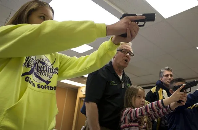 Instructor Jerry Kau (C) shows students Samantha Dolatowski (L) and Joanna Zuber how to hold a handgun during a Youth Handgun Safety Class at GAT Guns in East Dundee, Illinois, April 21, 2015. (Photo by Jim Young/Reuters)