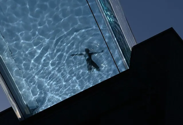 A person relaxes during hot weather at the Embassy Gardens Sky Pool, a transparent acrylic swimming pool suspended between two buildings, in London, Britain, September 7, 2021. (Photo by Toby Melville/Reuters)