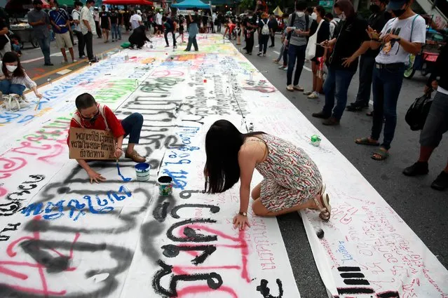 People write on a poster during a protest over the Thai government's handling of the coronavirus pandemic and to demand Prime Minister Prayuth Chan-ocha's resignation, in Bangkok, Thailand, September 3, 2021. (Photo by Soe Zeya Tun/Reuters)