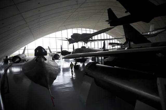 A man walks through aircrafts and other items on display during a media event to mark the reopening of the American Air Museum after it underwent a major redevelopment, at the Imperial War Museum of aviation in Duxford, England, Wednesday, March 16, 2016. The transformed American Air Museum opens to the public from Saturday March 19 and tells the story of Anglo-American collaboration in 20th and 21st century conflict as seen through the eyes of the people linked with the aircraft and objects on display. (Photo by Matt Dunham/AP Photo)