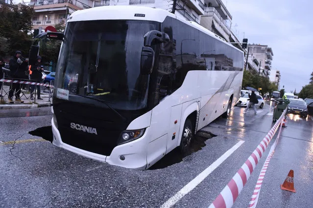 A view of a passenger bus after it fell with the front part into a five-meter pit while carrying 15 passengers, in a central avenue in Thessaloniki, northern Greece, 15 October 2021, as heavy rainfall hit the city. No injuries have been reported and the passengers were safely evacuated. (Photo by Dimitris Tosidis/EPA/EFE)