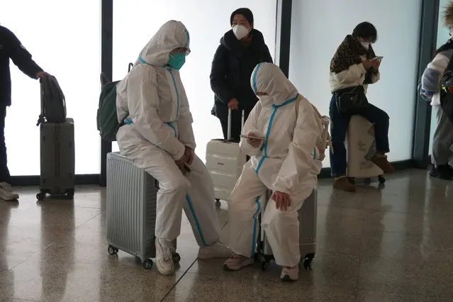 People wearing protective suits wait at a waiting hall of a railway station, after the government eased curbs on the coronavirus disease (COVID-19) control, in Wuhan, Hubei province, China on December 11, 2022. (Photo by Martin Pollard/Reuters)