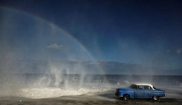 An old American car drives through Havana's Malecon on December 18, 2023. (Photo by Yamil Lage/AFP Photo)
