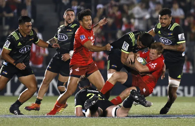 Sunwolves Hayden Parker, second from right, is tackled by Hurricanes defense during the Super Rugby game between the Hurricanes and Sunwolves in Tokyo, Friday, April 19, 2019. (Photo by Shuji Kajiyama/AP Photo)